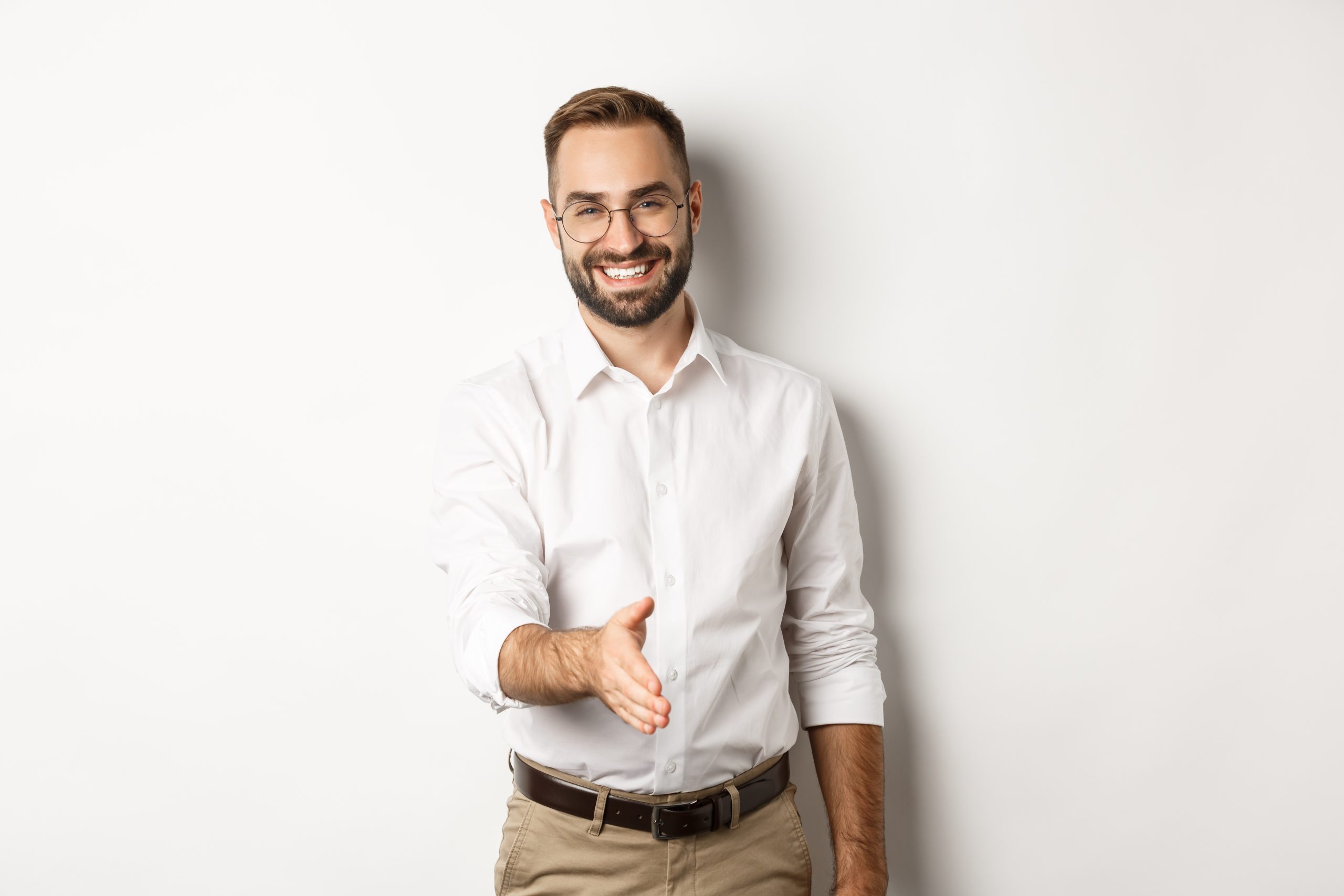 Confident businessman extending hand for handshake, greeting business partner and smiling, standing over white background